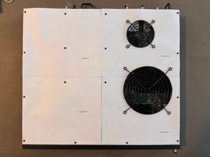 A top-down view of a rack-mount network switch, the Brocade ICX 7450-24, on a table, but with the top covered by 4 equal squares of printer paper, cut as templates for the replacement panels being designed.